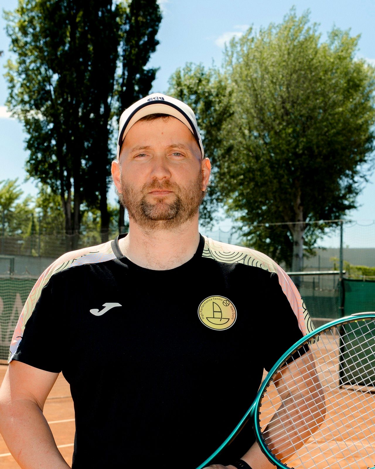 Ante Nakić Alfirević, Tennis Coach, mit Kappe und Schläger auf dem Sandplatz