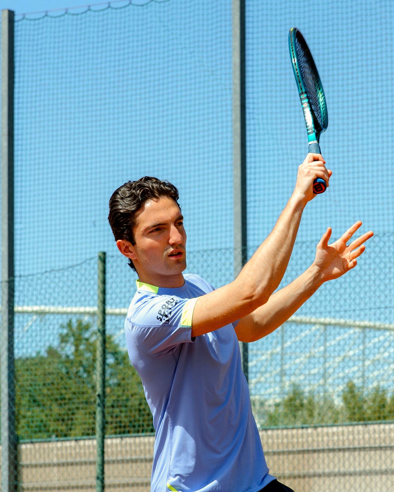Tarik Mustafič, Tennis Coach, beim Schlag mit erhobenem Schläger auf dem Sandplatz